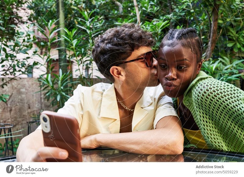 Unterschiedliches Paar macht Selfie im Garten Smartphone Kuss Termin & Datum schmollende Lippen Zusammensein Liebe Sommer Freundin Wange vielfältig