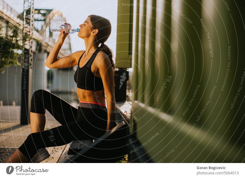Hübsche junge Frau, die eine Pause macht, während sie draußen trainiert und Wasser trinkt sportlich Kaukasier Großstadt Übung passen Fitness Gesundheit