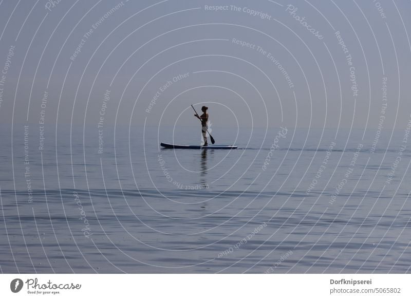 Frau mit Stand Up Board SUP-Board auf dem Meer supboard Standuppaddling Paddel Bootsfahrt stehen blau Ostsee Baltic Sea Horizont Wasser Sport Hobby spass lustig