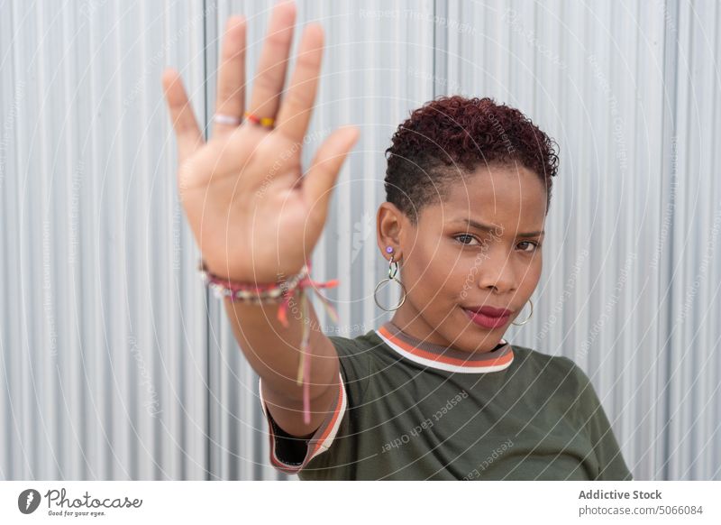 Kolumbianerin zeigt Stopp-Geste Frau stoppen gestikulieren Straße ernst Stirnrunzeln Wand urban Porträt Vorschein schwarz ethnisch kolumbianisch verbieten