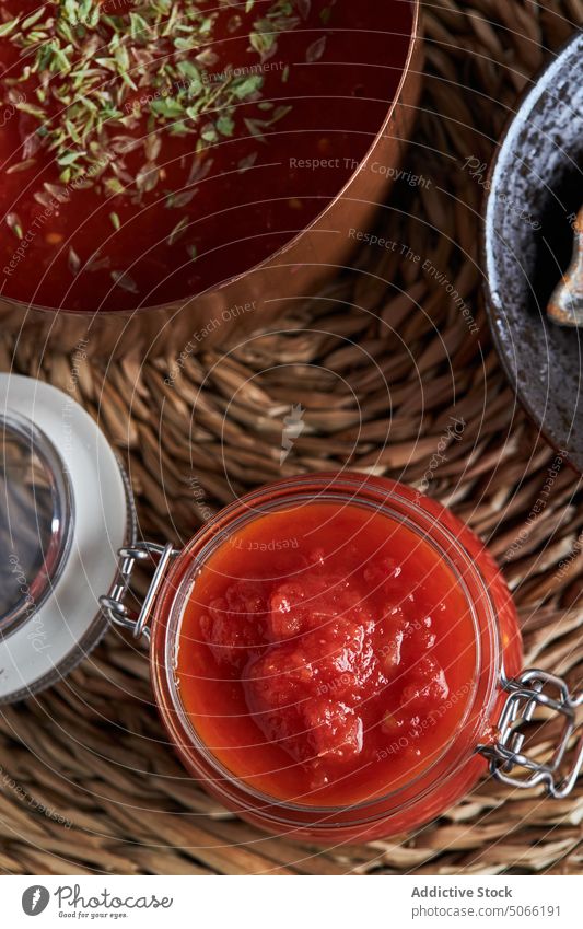 Behälter und Pfanne mit Tomatensauce auf dem Tisch Saucen Container bestäuben Zusammensetzung selbstgemacht gewebt Unterlage Oregano Küche heimwärts Kochtopf