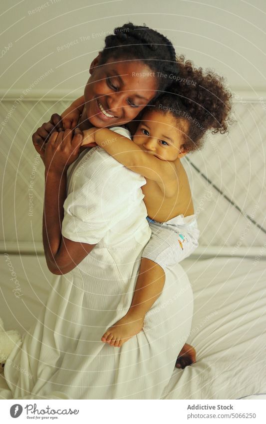Glückliche schwarze Mutter trägt Mädchen auf dem Rücken Tochter Huckepack Liebe heimwärts Kind Bett Partnerschaft Frau Lächeln Zeit verbringen ethnisch