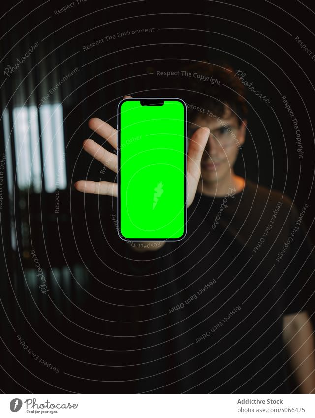 Mann zeigt Smartphone mit grünem Bildschirm Telefon Nachricht Funktelefon digital Apparatur Mobile Gerät Internet manifestieren zeigen inserieren