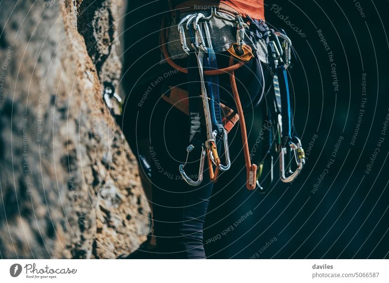 Detail der Kletterausrüstung, die an einem Klettergurt einer Frau befestigt ist, während sie eine Route klettert Aktivität Abenteuer Alpinismus Leichtmetall