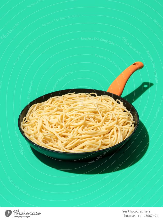 Spaghetti in einer Eisengusspfanne isoliert auf grünem Hintergrund hell Kohlenhydrate Farbe Essen zubereiten Textfreiraum kreativ Küche ausschneiden Design