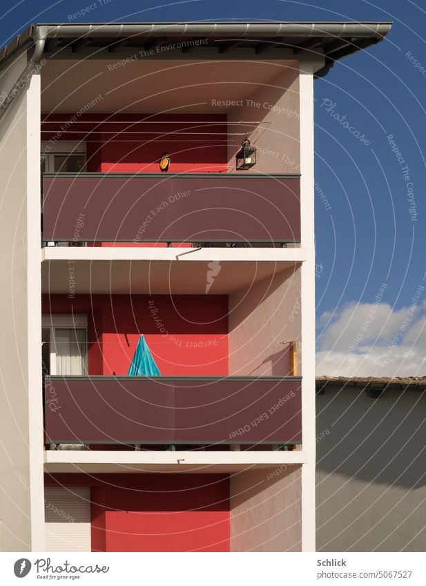 Farbkontrast rot und blau Balkone und Sonnenschirm geschlossen Wohnhaus detail wohnen Sonnenschein Himmel Gebäude Regenfallrohr Dachrinne Wäscheleine Beton