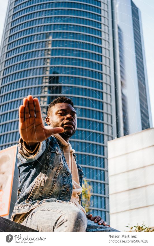 Porträt eines selbstbewussten jungen schwarzen Mannes mit einem Gebäude im Hintergrund Model Ausdruck Stil Afro-Look sozial Gesicht Person Typ Amerikaner Straße