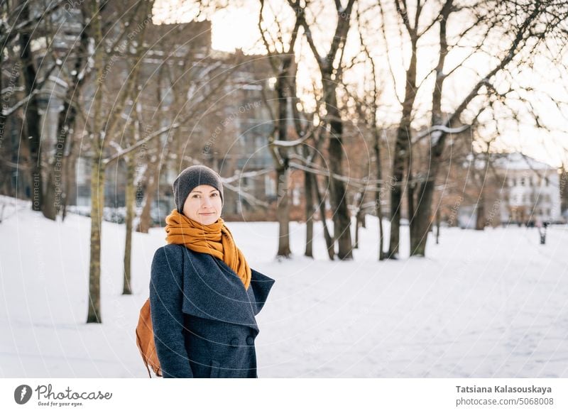 Eine Frau auf der Straße einer winterlichen Stadt schaut in die Kamera Winter kalt Schnee Fröhlichkeit Glück Freude Menschen Person Erwachsener Mantel
