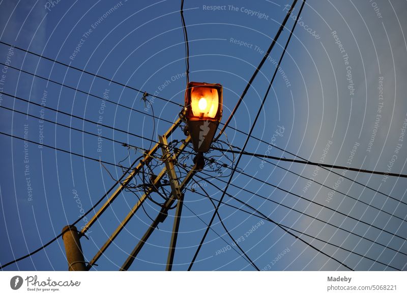 Stromleitungen mit Straßenbeleuchtung an einem Leitungsmast am Abend in Adapazari in der Provinz Sakarya in der Türkei Stromversorgung Elektrizität Kreuzung