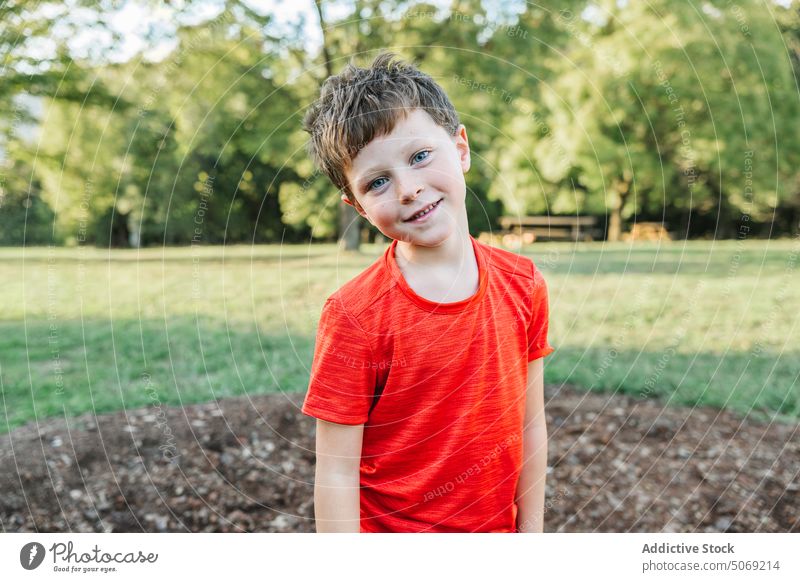 Fröhlicher Junge im Sommerpark Park Lächeln positiv tagsüber Rasen Wochenende Porträt Vorschein Kind T-Shirt Glück Kindheit heiter Optimist freundlich lässig