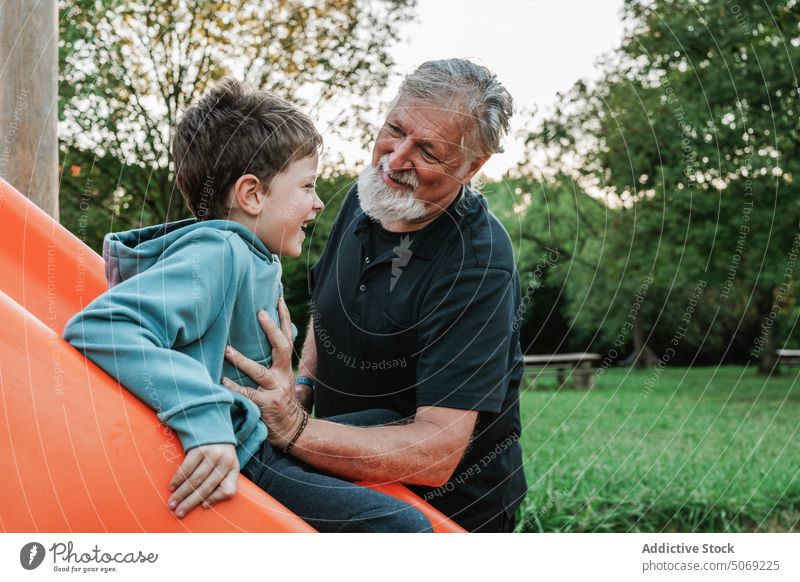 Enkel spielt auf der Rutsche neben dem Großvater Sliden spielen heiter Lächeln Wochenende Sommer Zusammensein Spielplatz Mann Junge Kind älter Senior gealtert