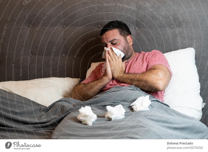 Mann mittleren Alters liegt mit Grippesymptomen im Bett 30 Personen Schmerzen allein Appartement Vollbart kalt Erkältungssymptom Coronavirus COVID deprimiert