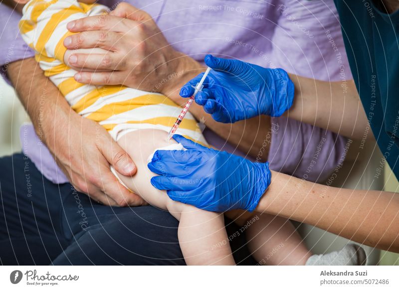 Weibliche Krankenschwester mit chirurgischer Maske und in Handschuhen gibt einem Baby in der Klinik eine Impfstoffinjektion. Impfung von Kleinkindern.