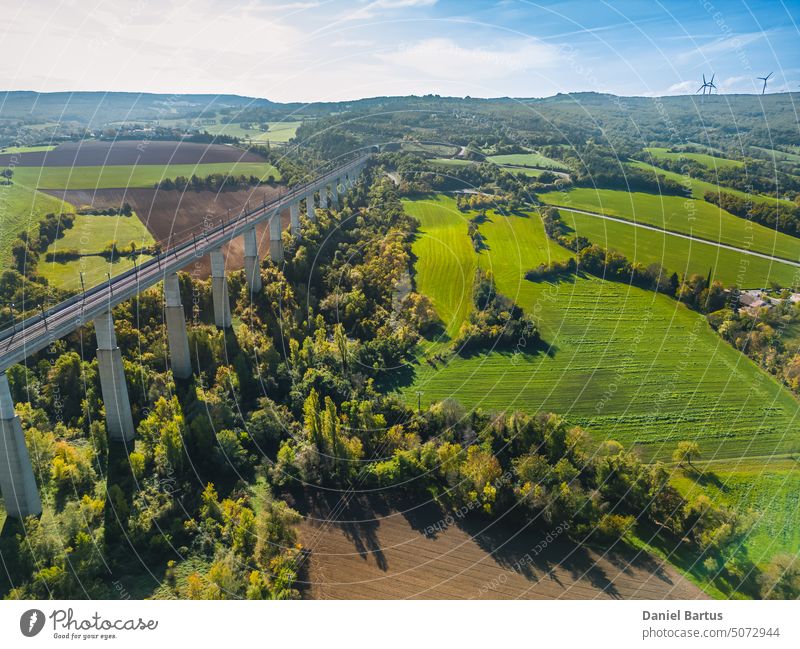 Blick aus der Luft auf die Gleise für Hochgeschwindigkeitszüge auf der Überführung. Herbstlicher Panoramablick auf die umliegenden Felder und Wälder und die umliegenden Berge.