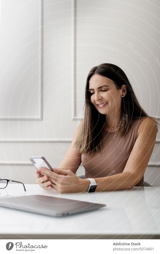 Glückliche Geschäftsfrau mit Smartphone in einem modernen, hellen Büro Frau Nachricht Unternehmer positiv Arbeit benutzend Lächeln Laptop Business