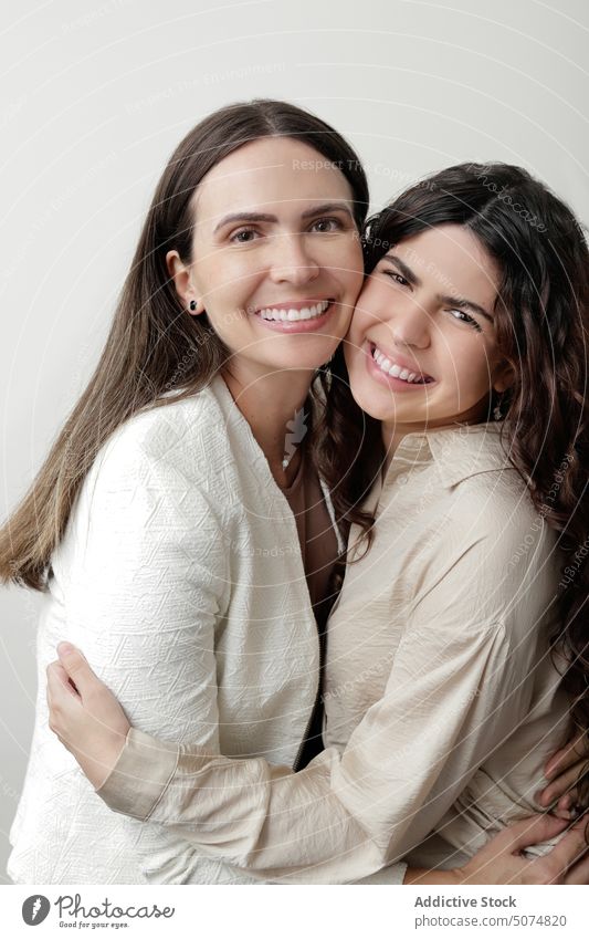 Zufriedene Mutter mit Tochter, die sich in einem weißen Studio umarmen und lächeln Frauen Umarmen Lächeln Liebe Partnerschaft Zusammensein positiv Porträt