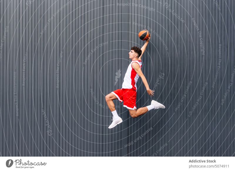 Männlicher Basketballspieler mit Ball vor dunklem Hintergrund Porträt Sportler Spieler springen Sprung Streetball Halt spielen Sportpark Tor Akrobatik Mann