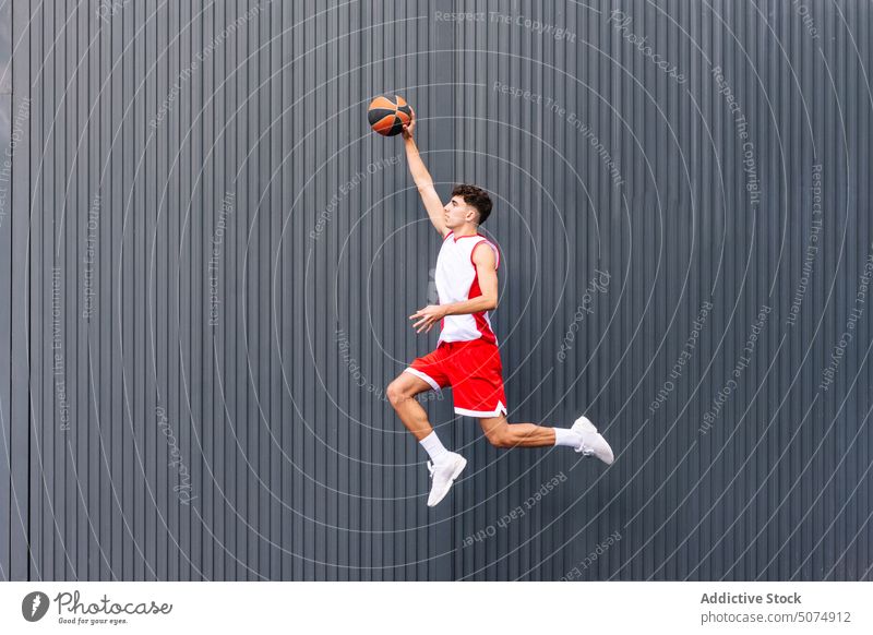 Männlicher Basketballspieler mit Ball vor dunklem Hintergrund Porträt Sportler Spieler springen Sprung Streetball Halt spielen Sportpark Tor Akrobatik Mann
