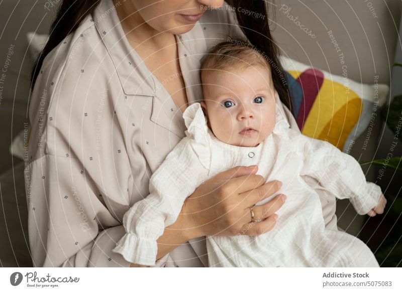 Anonyme junge Mutter, die ihren Säugling streichelt Baby Umarmung Streicheln Sofa Wohnzimmer heimwärts Liebe Morgen Frau Angebot friedlich Pyjama Zuneigung