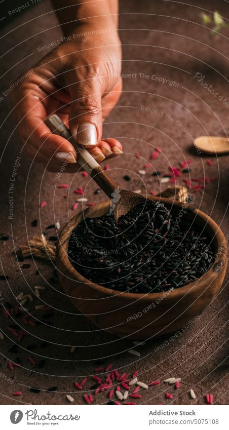 Crop-Frau zeigt schwarzen Reis zeigen Schalen & Schüsseln berühren frisch Eukalyptus Zweig Tisch Ast natürlich organisch Tageslicht Produkt filigran Angebot
