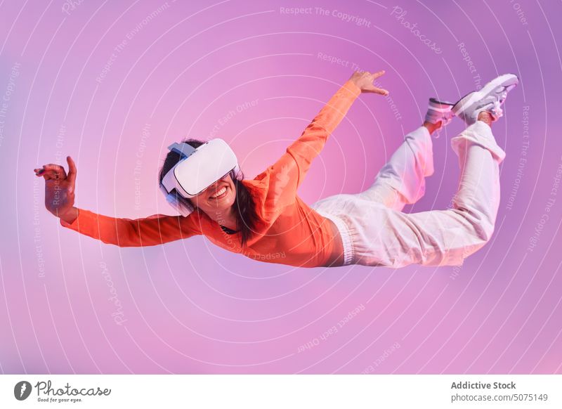 Frau mit VR-Brille schwebt in der Luft hängend Fliege fallen Air Konzept erkunden Erfahrung futuristisch eintauchen gestikulieren Stil farbenfroh Schutzhelm