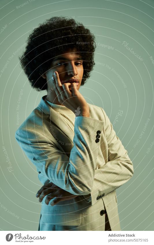 Junger hispanischer Mann berührt Gesicht Stil Wange berühren Windstille Vorschein Jacke Afro-Look Model Individualität smart lässig männlich jung ethnisch