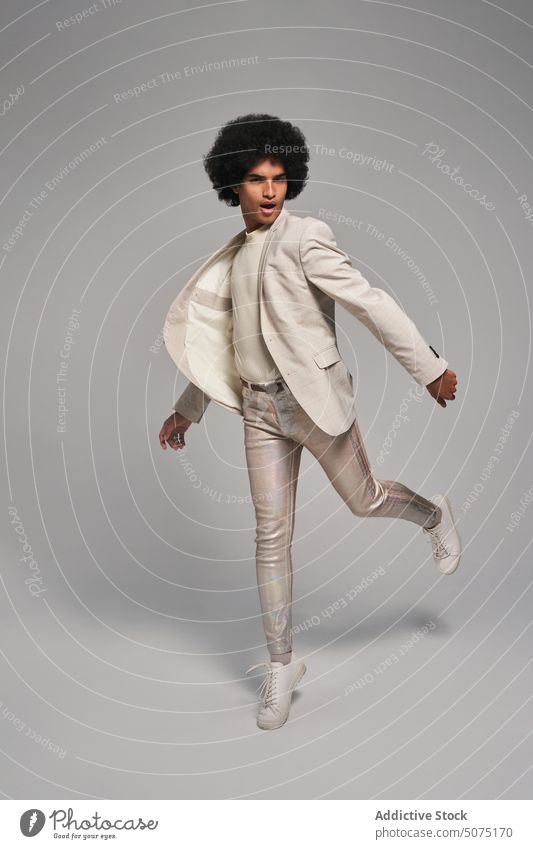 Stilvolles hispanisches Männchen, das vor grauem Hintergrund springt Mann springen Freiheit Energie modern Model Anzug dynamisch Aktivität männlich jung