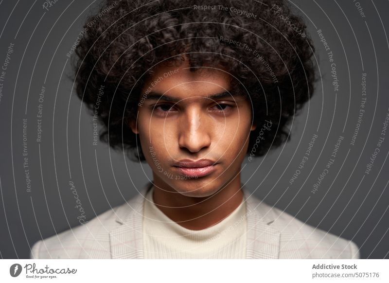 Junger hispanischer Mann schaut in die Kamera Stil ernst smart lässig Vorschein Porträt krause Haare Rollkragenpulli Jacke Model männlich jung ethnisch