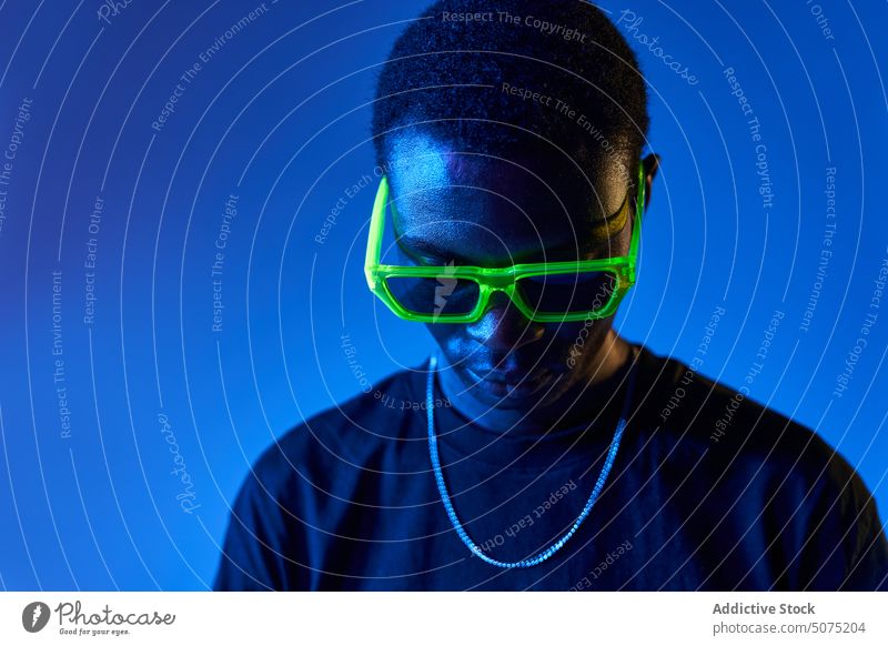 Schwarzer Mann mit stylischer Sonnenbrille im Neonlicht selbstbewusst Stil Metaversum neonfarbig Licht selbstsicher ultraviolett cool männlich jung