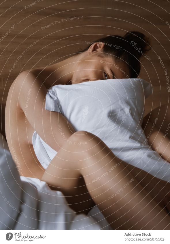 Frau entspannt sich auf dem Bett und umarmt das Kissen Schlafzimmer Sitzen sensorische Wahrnehmung menschlicher Körper Sinnlichkeit Schönheit Erholung aussruhen