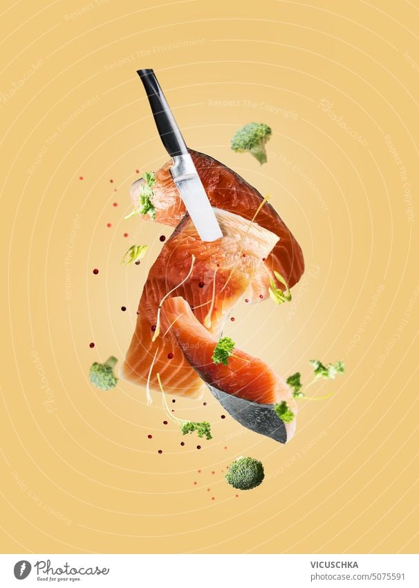 Fliegende Lachsfischfilets mit Messer, Kräutern und Gewürzen. Kreative Meeresfrüchte-Levitation fliegen Fischfilets Küchenkräuter kreativ Essen zubereiten Filet