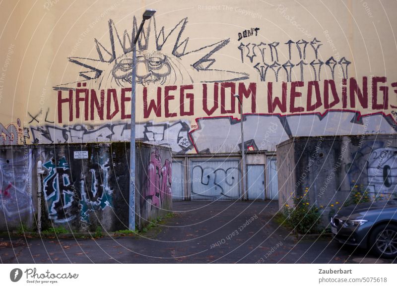 Hände weg vom Wedding - Parole auf einer Brandschutzwand, davor Garagen, Einfahrt und Straßenlaterne Berlin Graffiti street art Garageneinfahrt Wohnraum
