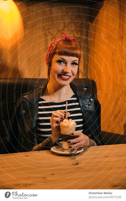 Porträt einer rothaarigen, attraktiven und lächelnden Frau, die in die Kamera schaut und mit einem Kaffee mit Sahne posiert. Inserat americano schön Getränk