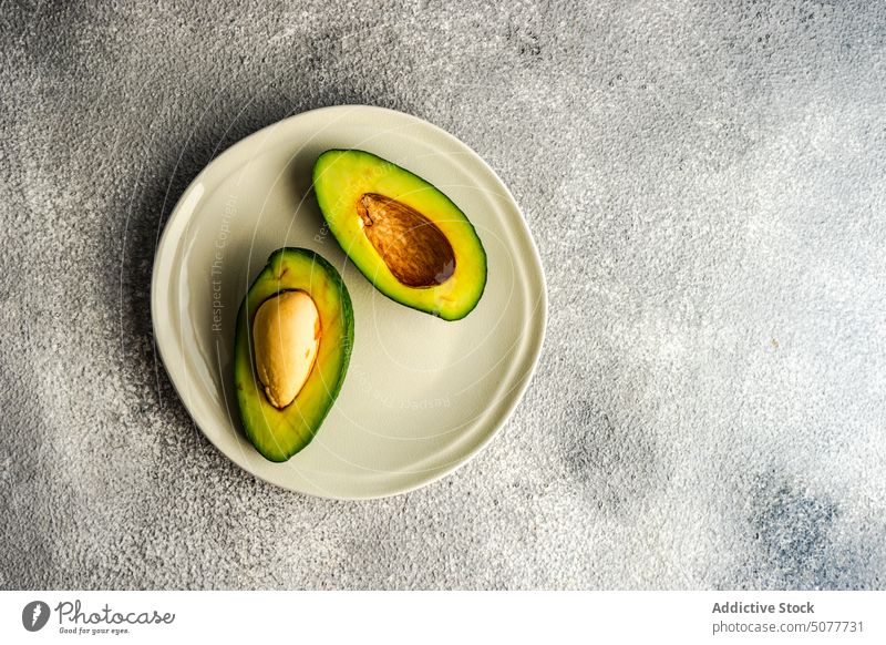 Die Hälfte der Avocado auf dem Teller Diät essen Fett Lebensmittel grau Beton Gesundheit Keton ketogen Küche Low Carb Mahlzeit roh organisch reif Scheibe Tisch