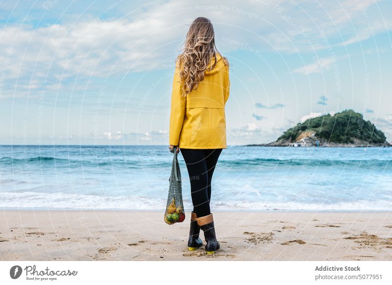 Frau mit Obst in der Tasche bewundert den Strand Frucht winken MEER Stehen sandig Wasser Apfel organisch Küste donostia Urlaub bewundern Natur Spanien nass