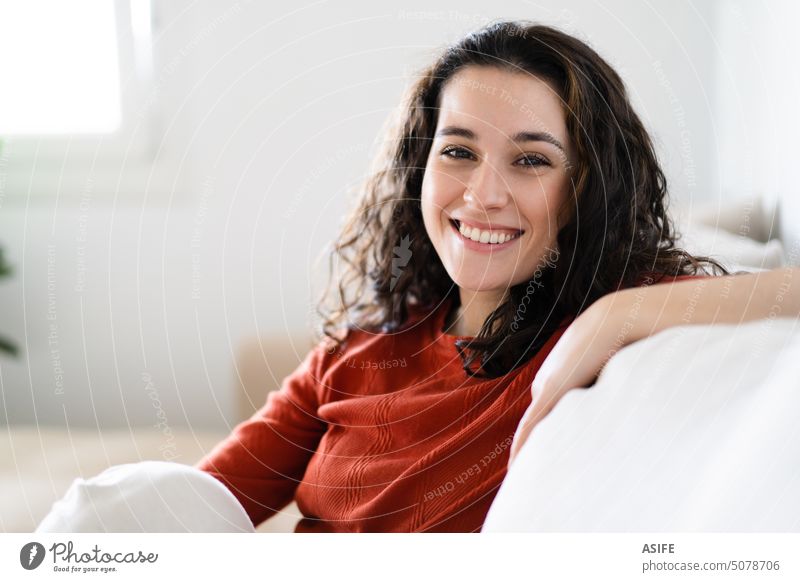 Porträt einer schönen jungen glücklichen Frau, die sich zu Hause auf der Couch entspannt heimwärts Liege Glück Lächeln zahnfarben in die Kamera schauen Freizeit