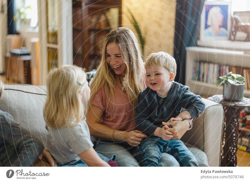 Mutter mit Kindern, die zu Hause auf dem Sofa sitzen reales Leben echte Menschen Bonden Familie im Innenbereich qualitätsvolle Zeit Kindererziehung Genuss Tag