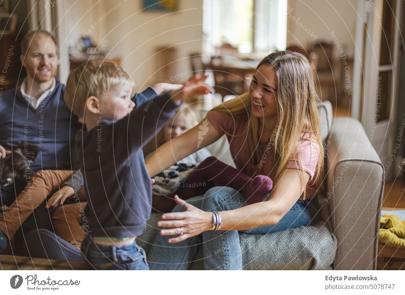 Glückliche junge Familie, die eine schöne Zeit zu Hause verbringt reales Leben echte Menschen Bonden im Innenbereich qualitätsvolle Zeit Kindererziehung Genuss