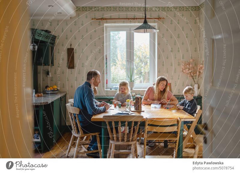 Glückliche junge Familie am gemeinsamen Esstisch zu Hause reales Leben echte Menschen Bonden im Innenbereich qualitätsvolle Zeit Kindererziehung Genuss