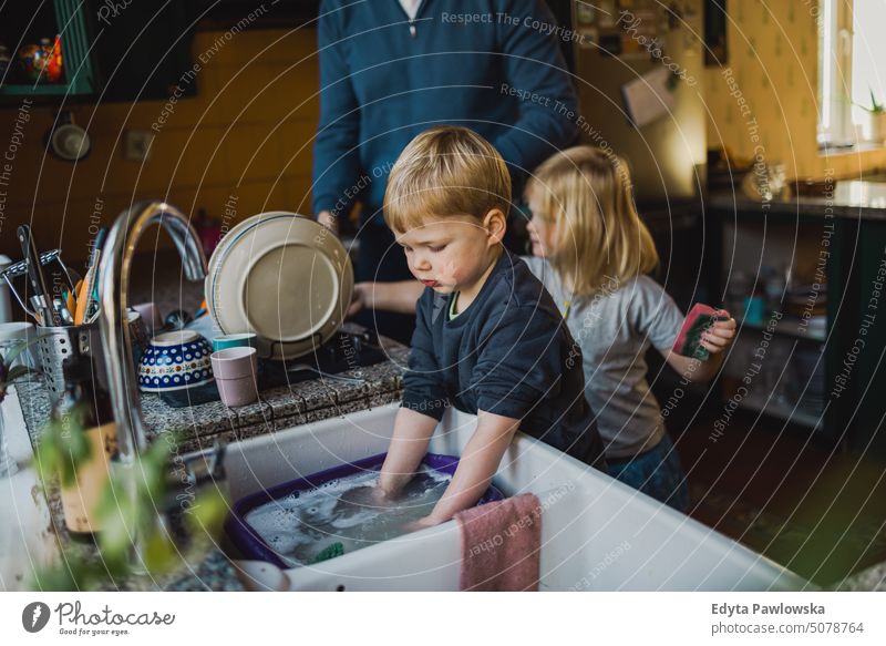 Kinder helfen Vater beim Abwasch in der Küche reales Leben echte Menschen Bonden Familie im Innenbereich qualitätsvolle Zeit Haus Kindererziehung Genuss Tag