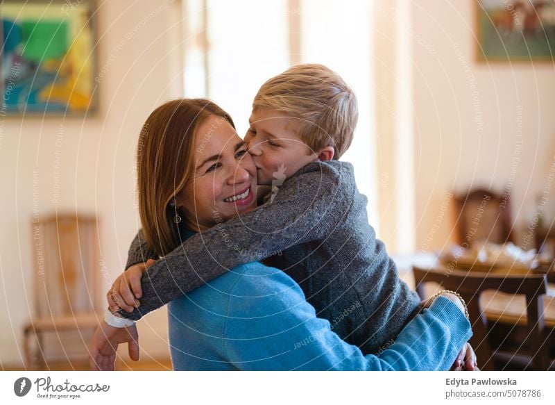 Sohn umarmt seine Mutter und küsst sie auf die Wange reales Leben echte Menschen Bonden Familie im Innenbereich qualitätsvolle Zeit Haus Kindererziehung Genuss