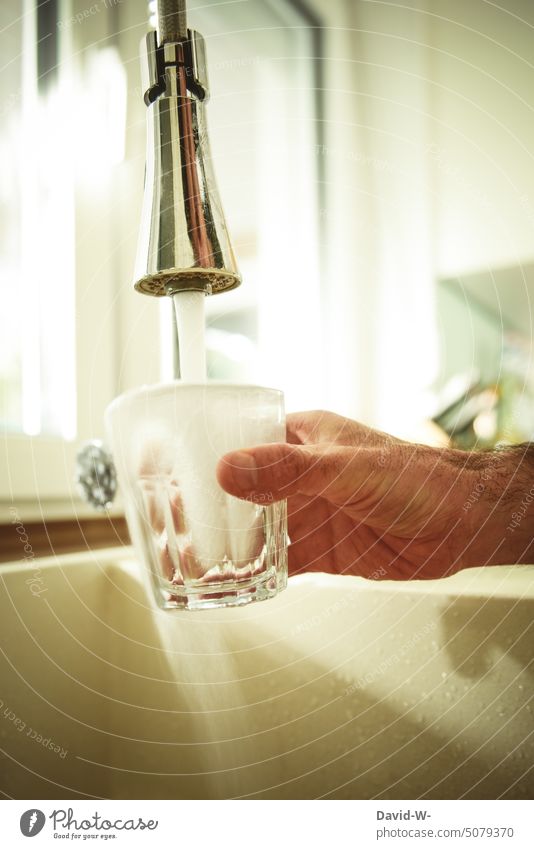 ein Glas mit Wasser auf dem Wasserhahn füllen Trinkwasser Durst Wasserverschwendung wasserverbrauch trinken Hand auffüllen