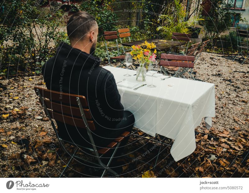 ein Mann am mit Schnittblumen gedeckten Tisch gedeckter Tisch Feste & Feiern Dekoration & Verzierung Serviette Blumenstrauß Stil Natur Besteck Vorfreude Mensch
