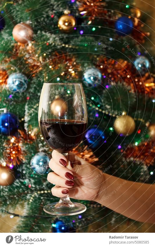 Frauenhand hält ein Glas Rotwein Hand Wein rot Alkohol Weihnachtsbaum Party trinken Restaurant schön Erwachsener im Innenbereich Hintergrund jung Weinglas