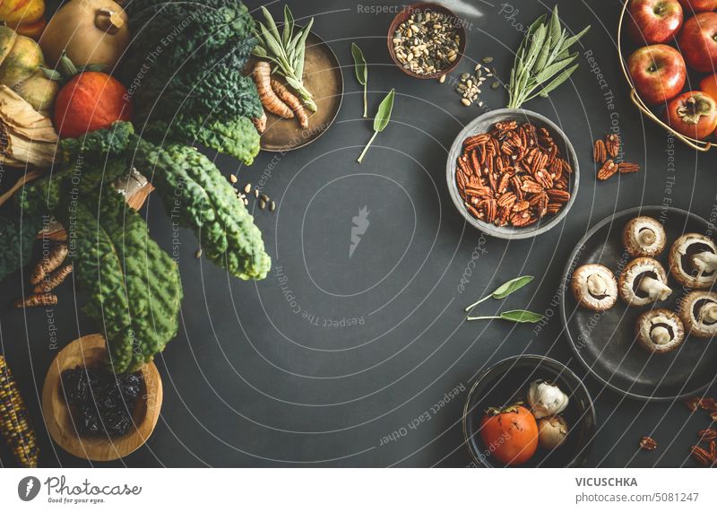Seasonal food background with organic vegetables from garden in basket: kale, pumpkins,apples and other ingredients für autumn or winter cooking. Top view. Frame