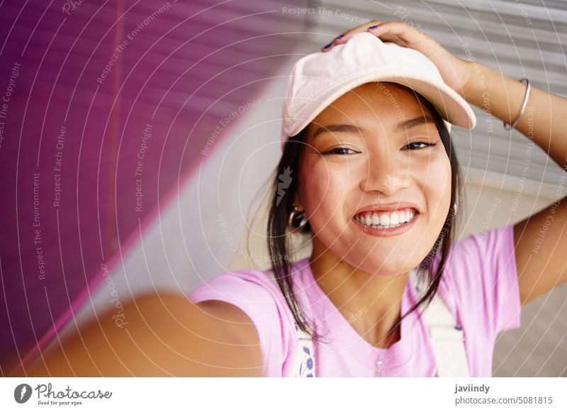 Fröhliche asiatische Frau nimmt Selfie auf der Straße Lächeln Stil Glück urban Vorschein Tastkopf Verschlussdeckel jung ethnisch dunkles Haar positiv