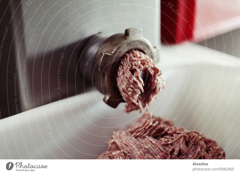 Fleischwolf, aus dem Hack in eine weiße Wann herausquellt - Wurstherstellung Maschine Handwerk Fleischer Fleischerei Herstellung Produktion