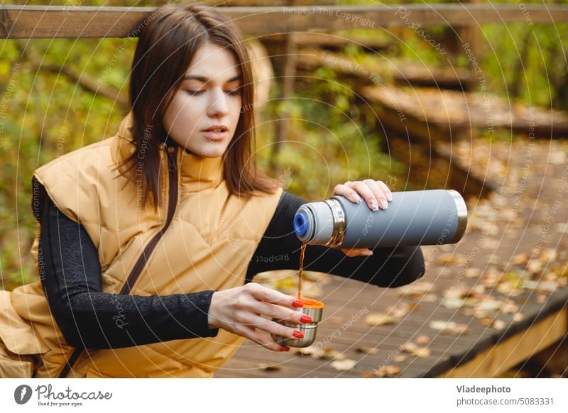 Frau auf Wanderschaft trinkt heißes Getränk aus Thermoskanne im Herbstwald Wald trinken Natur Kaffee Tee Ausflug reisen Person Tasse fallen im Freien Mädchen