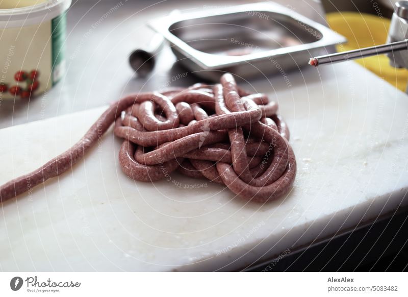 Frisch hergestellte Wurstschlange, die neben einer Wurstfüllmaschine liegt Maschine Handwerk Fleischer Fleischerei Herstellung Produktion