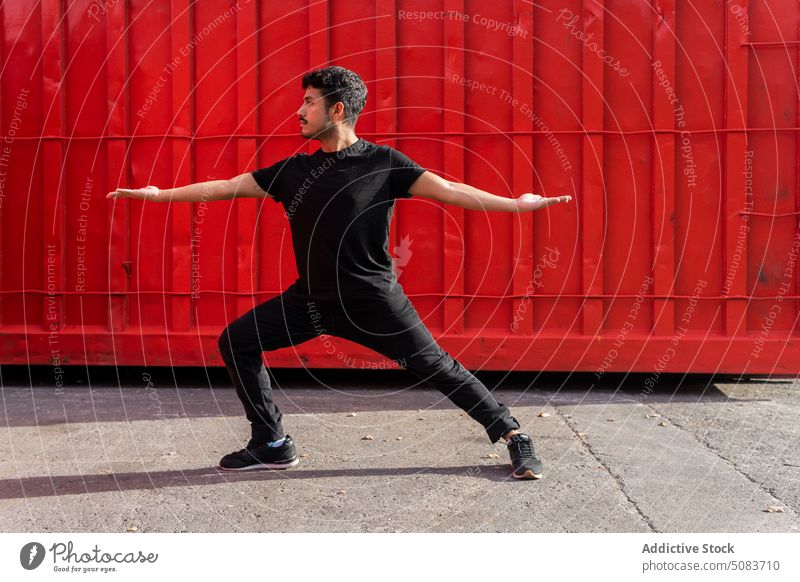 Junger Mann tanzt gegen roten Zaun Tanzen Gleichgewicht üben Tänzer Arm angehoben ausführen Talent Straßenbelag Fähigkeit männlich Choreographie Probe
